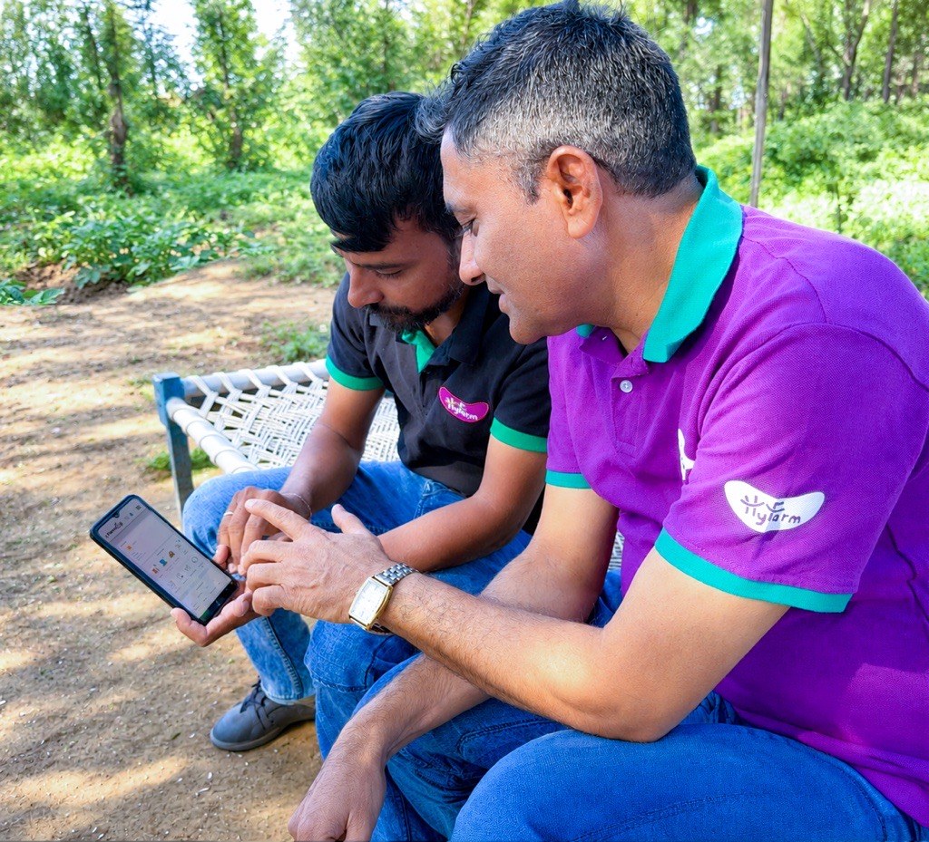 हाईफार्म के फ़ील्ड अफ़सर और एक आलू किसान फ़ोन पर फ़ार्मओजी ऐप देखते हुए